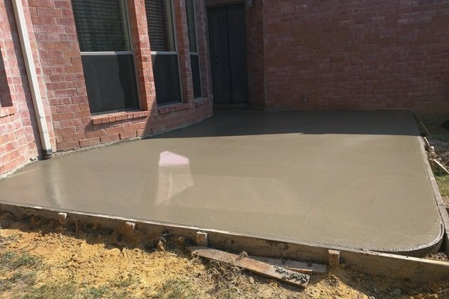 Concreter using a level to ensure the accuracy of a newly poured concrete slab